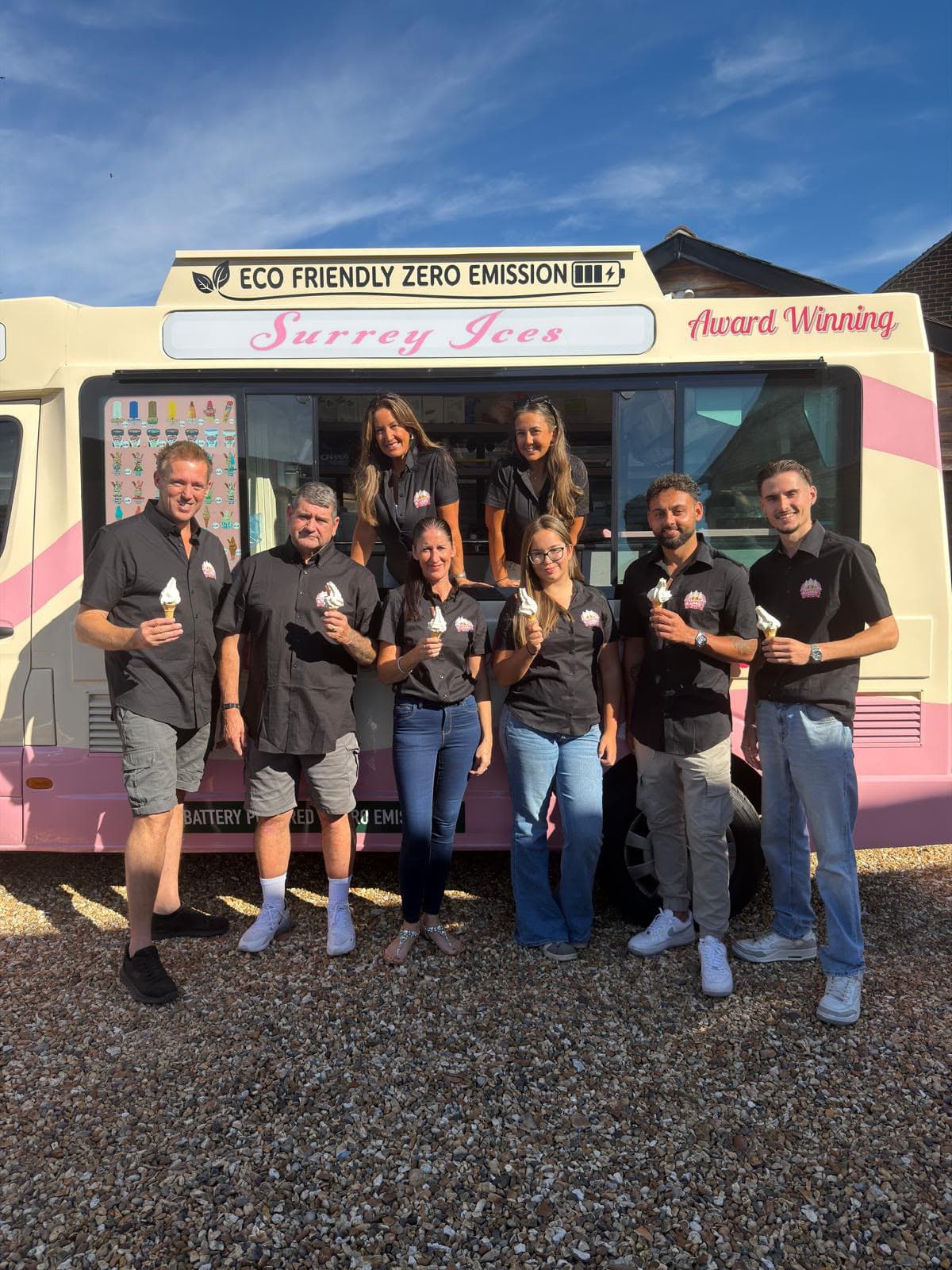 The Hampshire Ices team standing in front of a pink and cream ice cream van, each holding a cone