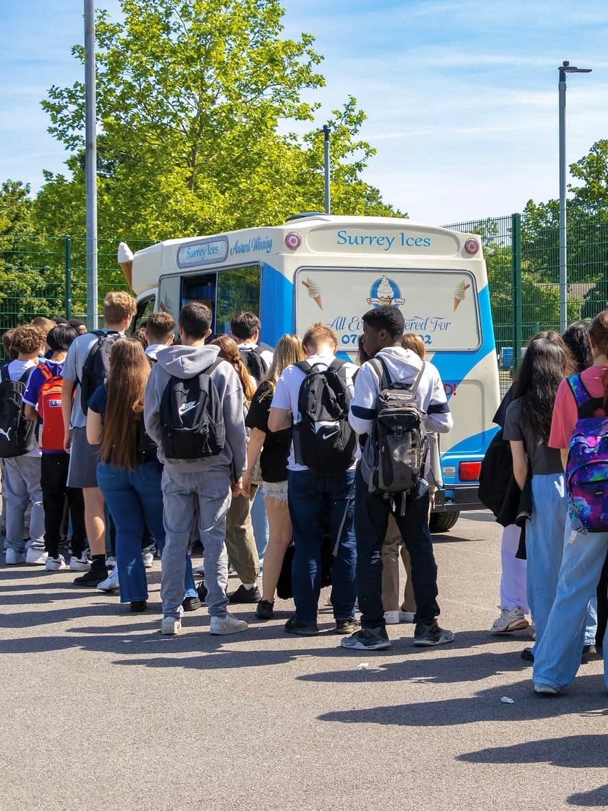 A queue of people waiting at a blue and cream Hampshire Ices van